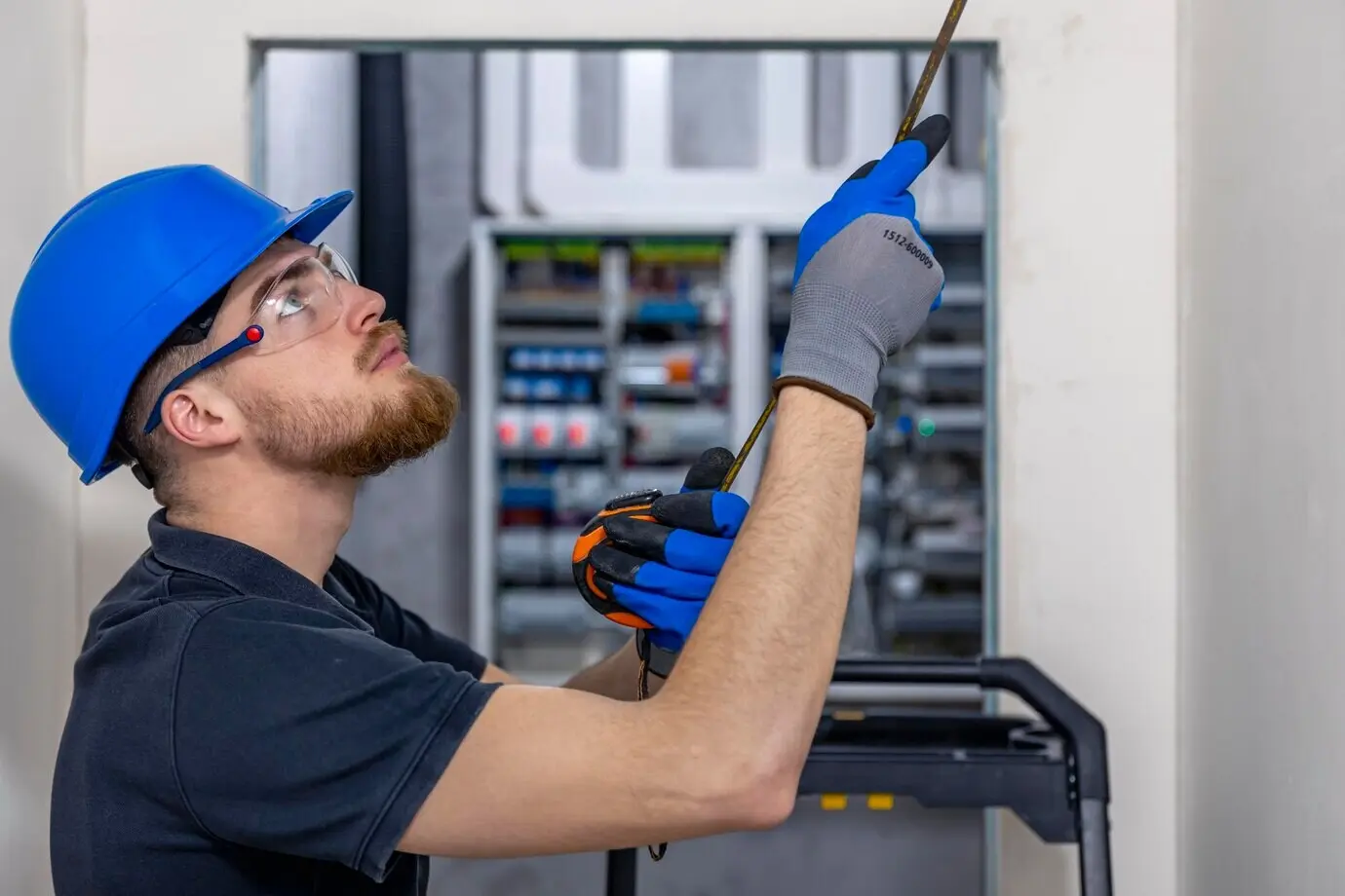 Электрик устанавливает и прокладывает электрические кабели на потолке внутри дома.